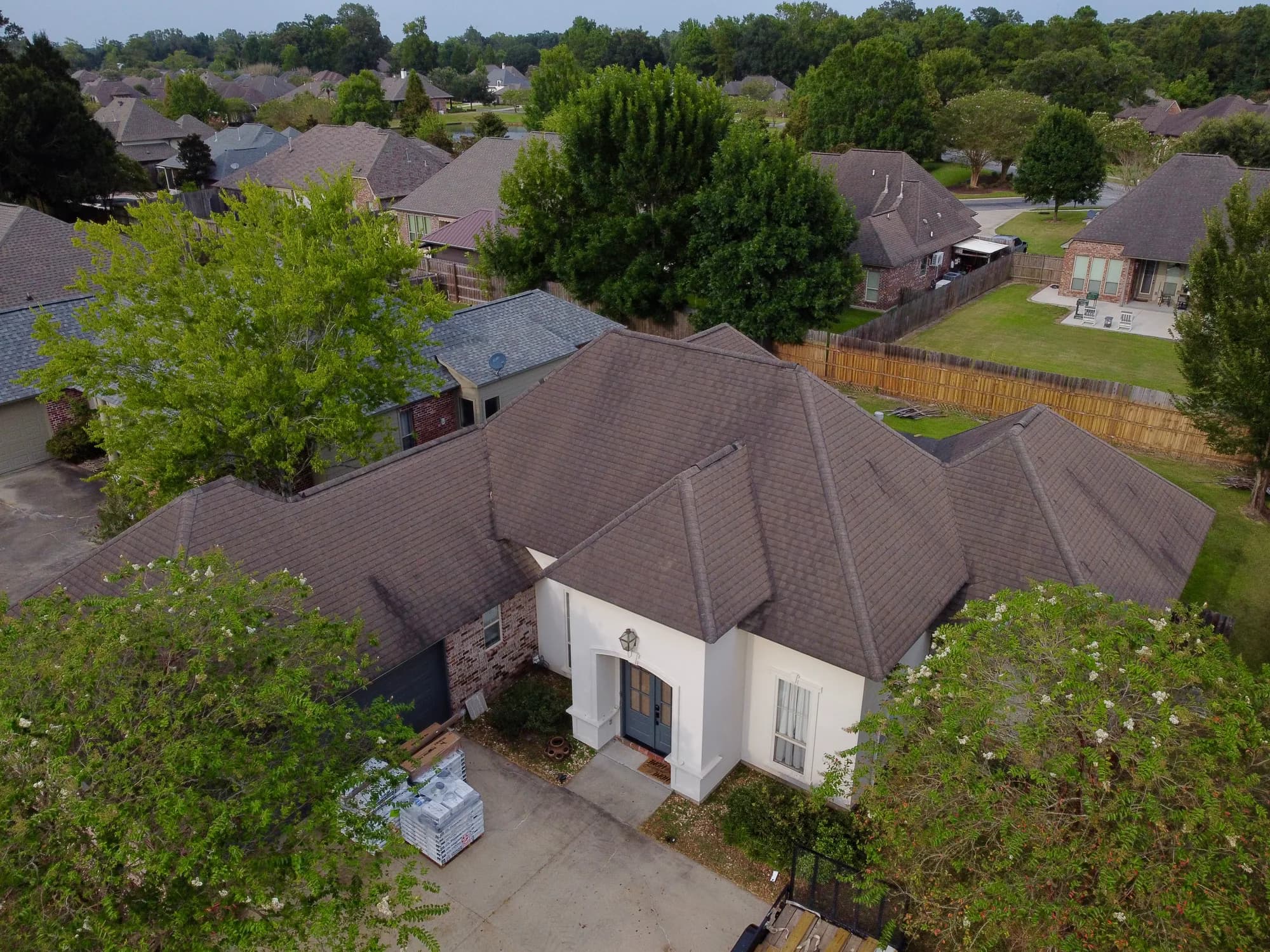 White brick home with aged dark roof before replacement